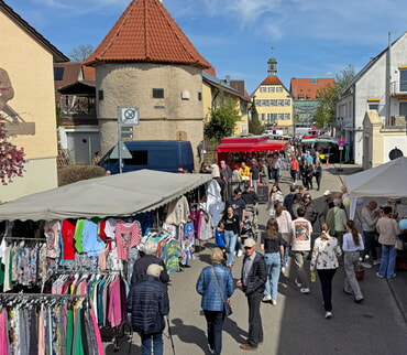 Menschen auf dem Ostermarktt. Im Hintergrund Geb&auml;ude und ein rotes Dach.