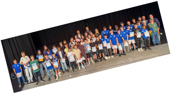 Gruppenfoto von Kindern und Jugendlichen mit Urkunden auf einer B&uuml;hne vor schwarzem Hintergrund.