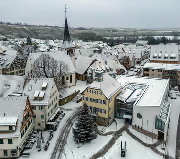 Schneebedeckte H&auml;user, Rathaus mit Rathausvorplatz und Kirche in einer Winterlandschaft, Blick von oben.